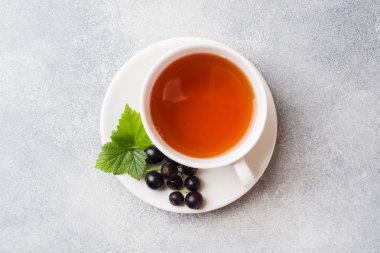 Gri masada bir fincan çay ve taze frenk üzümü meyveleri. Kopyalama alanı.