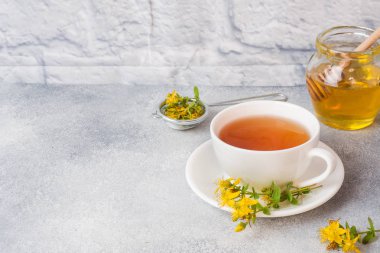 Yaprakları çiçek Hypericum gri arka plan bitkisel çay ile Fincan. Kopyalama alanı.