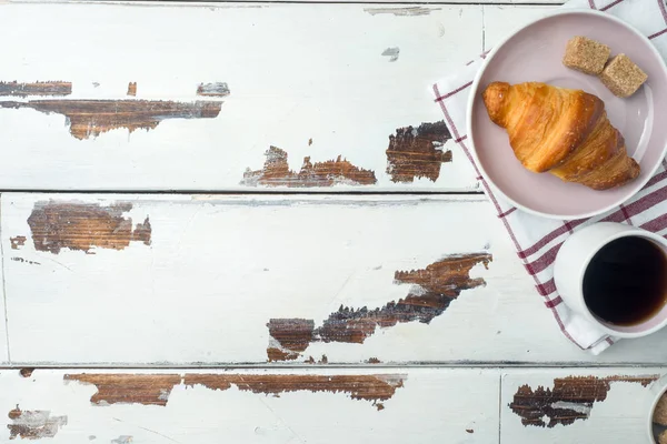 Petit déjeuner croissants sur une assiette et une tasse de café, fond en bois, espace de copie . — Photo