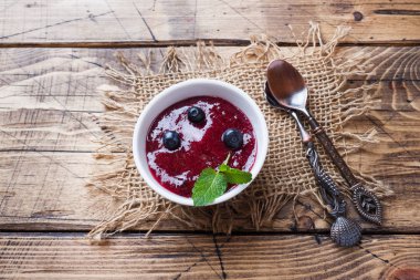 Bir tabakta yaban mersini reçeli ve ahşap bir masada taze yaban mersini.