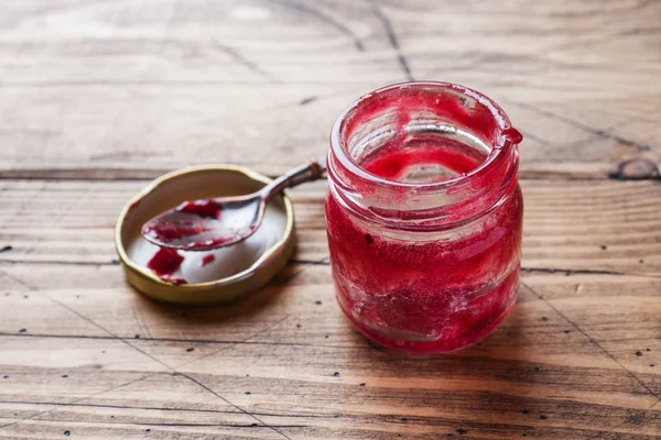 Empty jar of blueberry jam and a spoon on a wooden table. — Stock Photo, Image