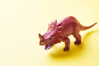 Sarı arka plandaki dinozor. Plastik kauçuk oyuncak. Seçici odaklama.