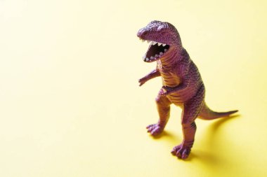 Sarı arka plandaki dinozor. Plastik kauçuk oyuncak. Seçici odaklama.