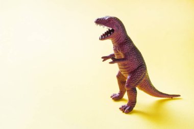 Sarı arka plandaki dinozor. Plastik kauçuk oyuncak. Seçici odaklama.