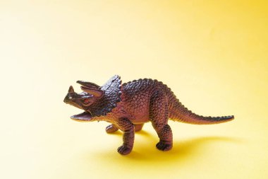 Sarı arka plandaki dinozor. Plastik kauçuk oyuncak. Seçici odaklama.