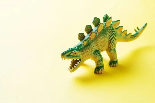 Dinosaurio sobre fondo amarillo. Juguete de goma plástico. Enfoque selectivo . —  Fotos de Stock