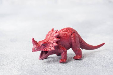 Gri arka plandaki dinozor. Plastik kauçuk oyuncak. Seçici odaklama.