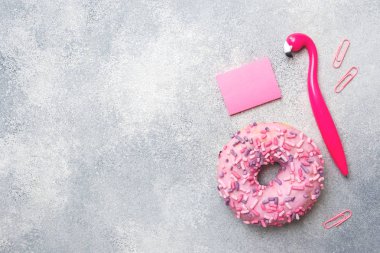 Gri bir arka plan üzerinde pembe çörek ve Flamingo kalem. Üstten düz yatıyordu.
