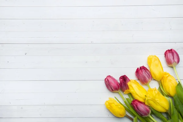 Ramo de tulipanes de color amarillo brillante y rosa sobre una mesa ligera con espacio para copiar . — Foto de Stock