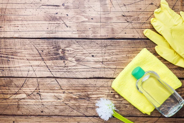 Bottles with detergents, brushes and sponges on wooden background. Colorful cleaning products. Home cleaning concept. Top view, copy space. — Stock Photo, Image