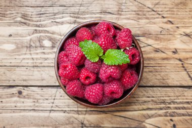 Ahşap bir tabakta taze kırmızı ahududu meyveleri.