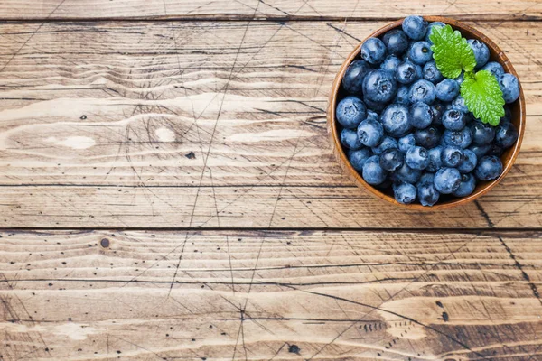 Fresh berries of ripe blueberries in a wooden plate. — Stock Photo, Image