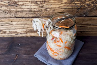 Ahşap arka planda cam kavanozda havuç ve kızılcık ile ev yapımı lahana turşusu. Boşluk Kopyala