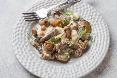 Bir tabakta ekşi krema ve peynir ile sos haşlanmış mantar