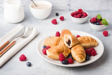 Koyu beton arka plan üzerinde taze ahududu ve yaban mersini ile Kruvasan. Kopya alanı. Kahvaltı kahve bal kavramı.
