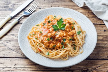 Spagetti makarna Bolognese beyaz tabakta, ahşap masa