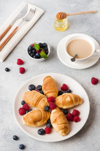 Croissants con frambuesas frescas y arándanos sobre un fondo de hormigón oscuro. Copiar espacio. concepto de desayuno café miel . — Foto de Stock