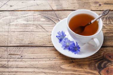 Ahşap masa üzerinde hindiba içecek ve mavi hindiba çiçekleri ile Fincan. Kopyalama alanı.