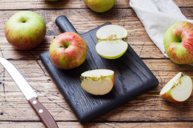 Tahta bir masanın üzerinde kırmızı elmalar var. Elmalar dilimler halinde kesilir. Kopyalama alanı.