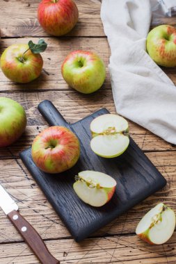 Tahta bir masanın üzerinde kırmızı elmalar var. Elmalar dilimler halinde kesilir. Kopyalama alanı.