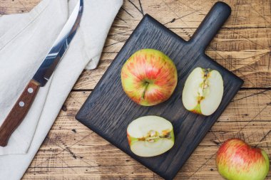Tahta bir masanın üzerinde kırmızı elmalar var. Elmalar dilimler halinde kesilir. Kopyalama alanı.
