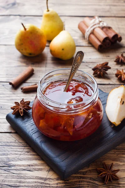 Confiture de poires maison dans un bocal et des poires fraîches sur un fond en bois. — Photo