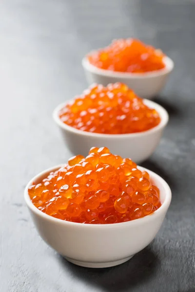 Red salmon caviar in a plate on a dark table. — Stock Photo, Image