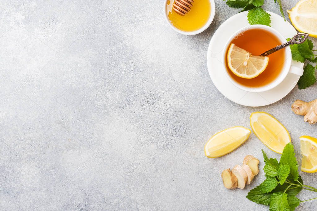 White Cup with natural herbal tea ginger lemon mint and honey. Gray background Copy space.