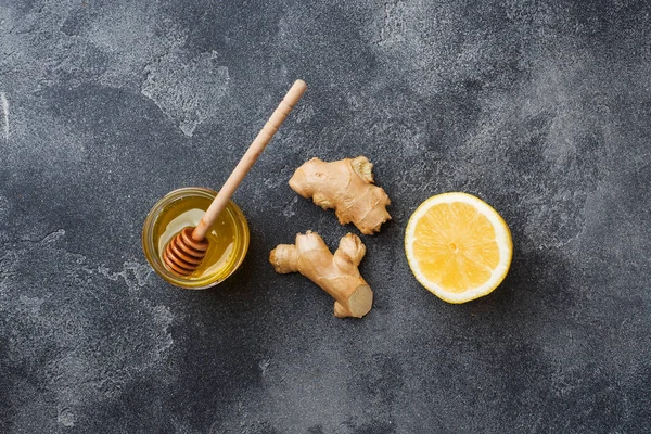 Zitronenhonig und Ingwerwurzel auf dunkelgrauem Hintergrund mit Kopierraum. Zutaten für ein stärkendes Vitamingetränk. — Stockfoto