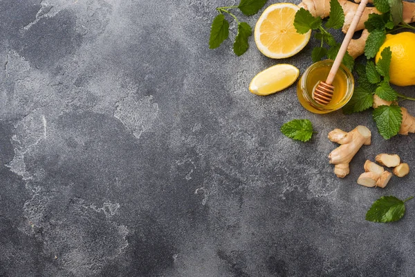 Zitronenhonig und Ingwerwurzel-Minze auf dunkelgrauem Hintergrund mit Kopierraum. Zutaten für ein stärkendes Vitamingetränk. — Stockfoto