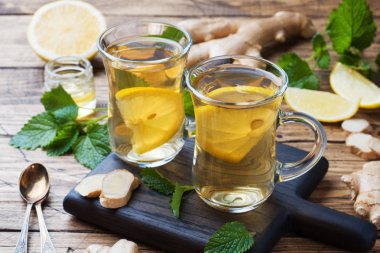 Ahşap bir arka plan üzerinde doğal bitkisel çay zencefil limon nane ve bal iki bardak.