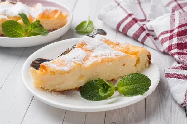 Cottage cheese casserole on a plate with powdered sugar and mint leaves. Selective focus — Stock Photo, Image