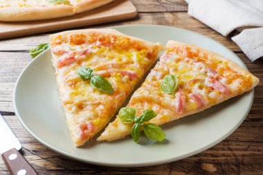 Ahşap bir masa üzerinde bir tabak üzerinde ev yapımı pizza parçaları.
