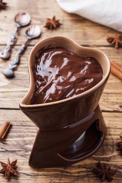 Chocolate paste with cinnamon and anise. Fondue with chocolate on a wooden table.