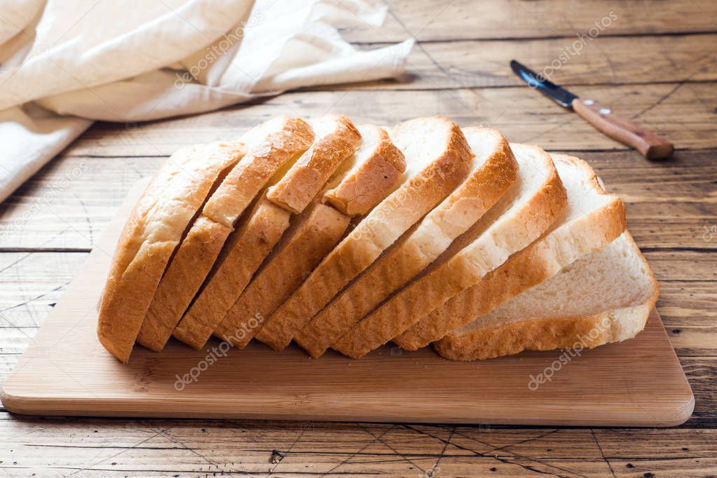 Pieces of white bread loaf for toast on a wooden table.
