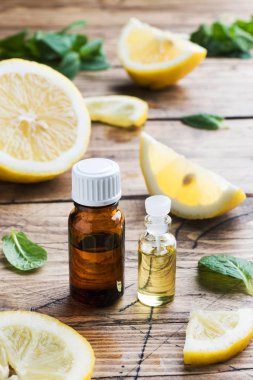 Şişede Uçucu limon yağı, ahşap sırt taze meyve dilimleri