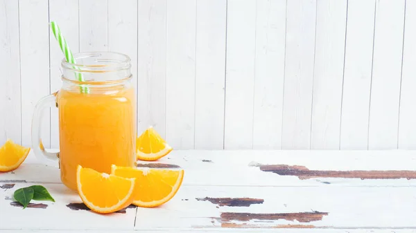 Orangensaft in Glasgläsern und frische Orangen auf weißem Holz — Stockfoto