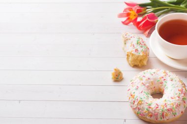 Çay ve çörekler Fincan, kopya alanı ile beyaz masada çiçek lale.