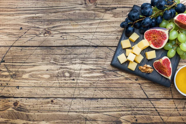 Cubos de queso, higos de fruta fresca uvas Nuez de miel sobre tabla de cortar de madera. Copiar espacio . — Foto de Stock