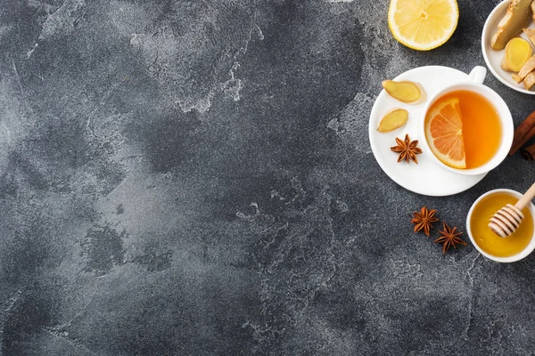 Tazza bianca con tisana naturale limone allo zenzero e cannella al miele. La bevanda vitaminica energetica viene utilizzata per i freddi. spazio copia di sfondo in cemento scuro — Foto Stock