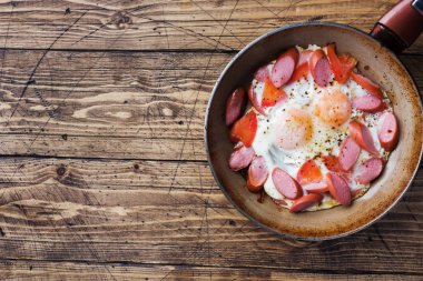 Masada kızarmış yumurta sosis ve domates ile tavada. Zengin ev yapımı Kahvaltı.