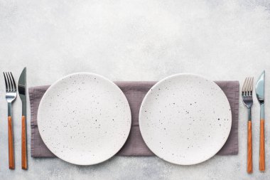 Açık beton zemin üzerinde iki boş seramik tabak. Üst görünüm.