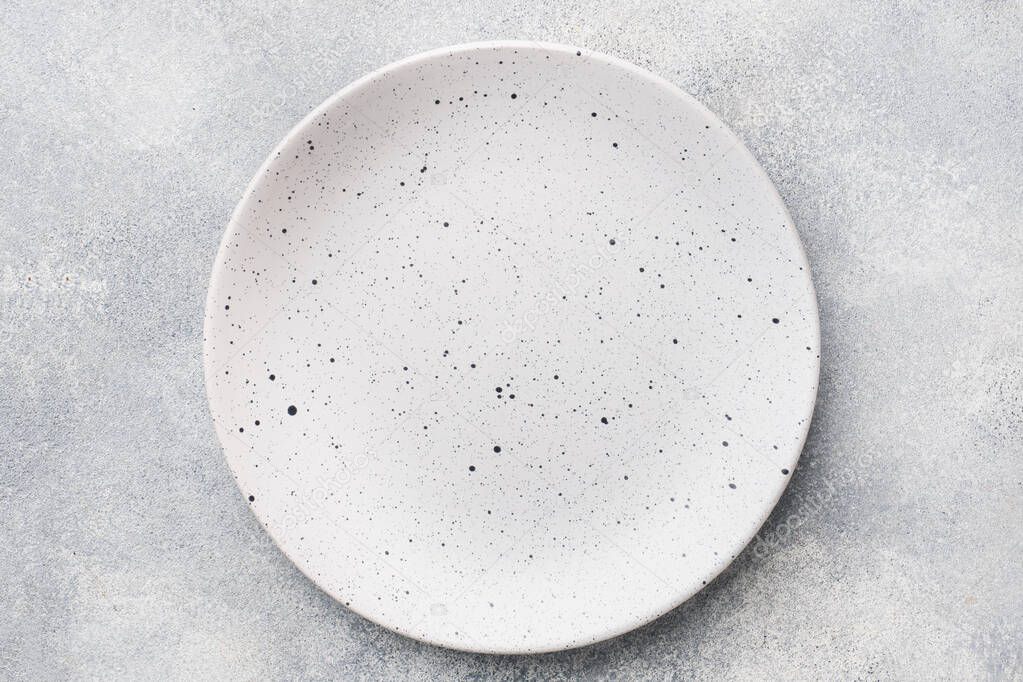 Empty ceramic plate on a light concrete background. Top view.