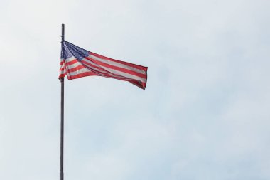 Mavi gökyüzünde dalgalanan Amerikan bayrağı.