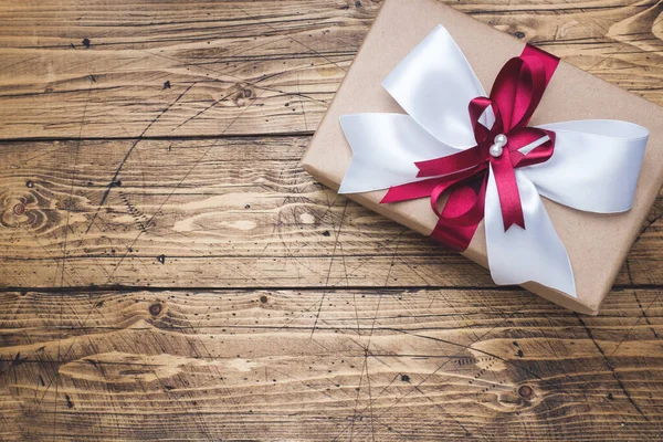 Подарункова або подарункова коробка з великим бантом на дерев'яному столі зверху. Творчість на Різдво, день матері або весілля . — стокове фото