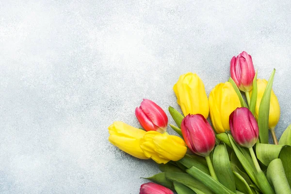 Ramo de tulipanes amarillos y rosados sobre un fondo azul claro. Copiar espacio —  Fotos de Stock