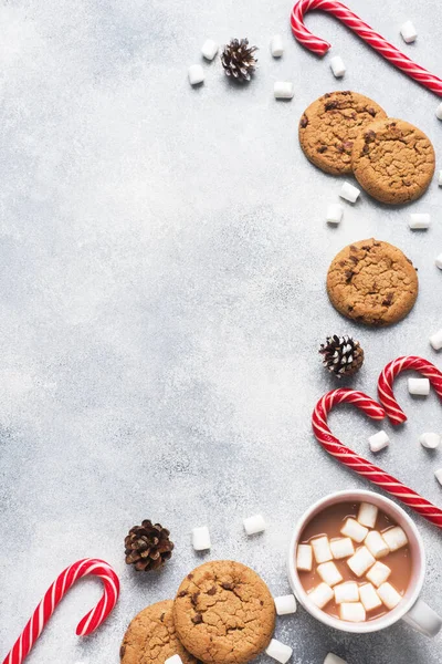 초콜릿 칩 쿠키, 크리스마스 사탕수수 캐러멜 컵 코코아, 마시멜로 콘 장식을 회색 배경으로 하고 있다. 복사 공간 프레임. — 스톡 사진