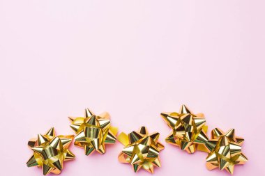 Pembe arka planda altın Noel yayları. Tatiller için hediye konsepti. Yeni yıl Noel Anneler Günü. Boşluğu kopyala.