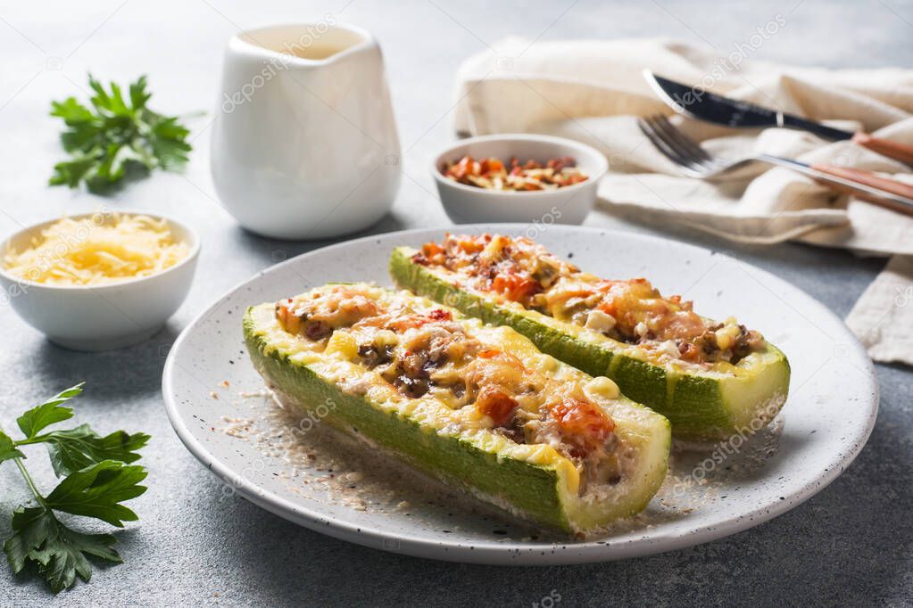 Baked stuffed zucchini boats with minced chicken mushrooms and vegetables with cheese on a plate.