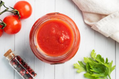 Kendi suyunda domates ya da cam kavanozda domates ve beyaz ahşap bir masada taze domates.